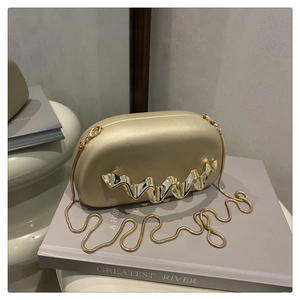 Detail of champagne gold evening clutch with wavy metal accent and gold snake chain strap