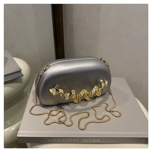 Close-up of silver evening bag featuring gold wavy metal trim and snake chain strap