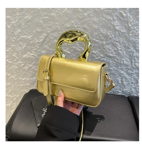 Detail of acrylic crossbody bag featuring a unique molten gold metal handle and glossy finish