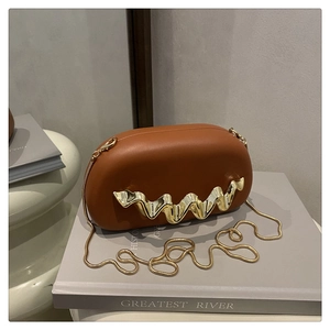Detail of caramel oval clutch with wavy gold metal trim and sleek snake chain strap