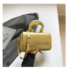 Close-up of a gold metallic handbag with unique liquid-style handle and fine shoulder strap