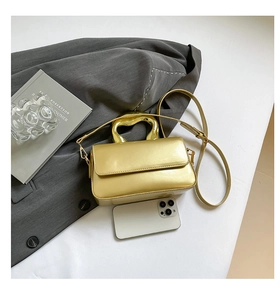 Macro view of bright gold acrylic handbag with unique metal handle and leather strap