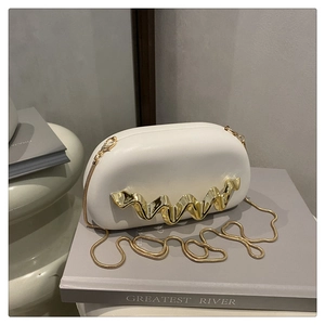 Close-up of white acrylic evening bag with wave gold metal decor and chain strap