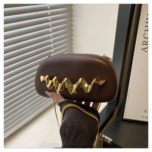 Detail view of brown acrylic clutch bag with gold wave handle and metal chain strap