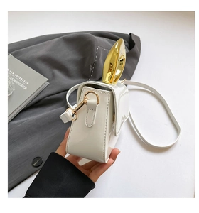 Detail view of white glossy crossbody bag featuring a unique gold metal handle and strap