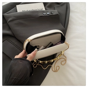 Detail view of white acrylic clutch bag showing interior space for phone and gold chain strap