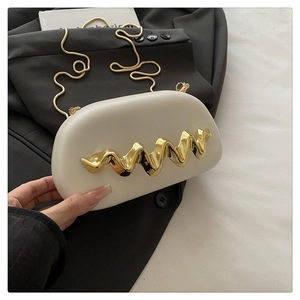 Close-up of white semi-circular acrylic evening bag with gold wave metal decoration
