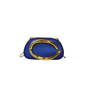 Detail of navy blue evening bag with oversized gold C-shaped metal hardware and chain