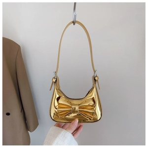 Détail d'un sac demi-lune doré effet miroir avec un grand nœud décoratif