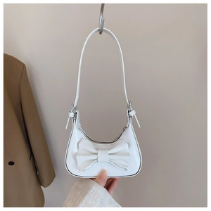 Gros plan d'un sac à main blanc en cuir verni brillant avec un grand nœud décoratif
