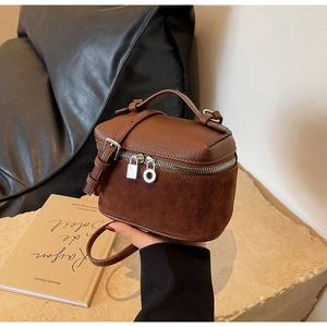 Detail of a brown leather box bag with pebble and suede textures and mini padlock