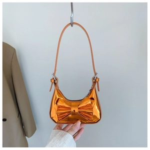 Détail du sac orange métallisé brillant avec grand nœud et fine bandoulière réglable