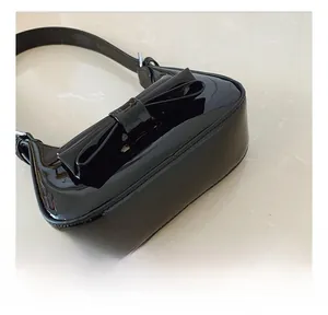 Détail du sac à main en cuir verni noir avec nœud et coutures de précision