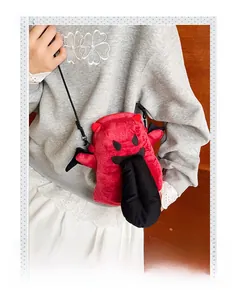 Détail du sac monstre en peluche rouge avec cornes de diable et ailes noires à bandoulière