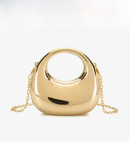 Close-up of golden crescent acrylic bag with mirror finish and elegant metal chain