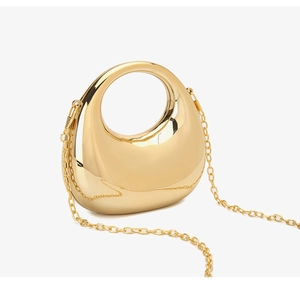 Detail of a metallic gold crescent bag with glossy finish and circular ring handle