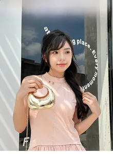 Outdoor lifestyle shot of a gold crescent acrylic mini bag with shiny metal chain