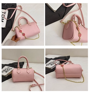 Pink litchi leather Boston bag with red strawberry charm and gold chain details