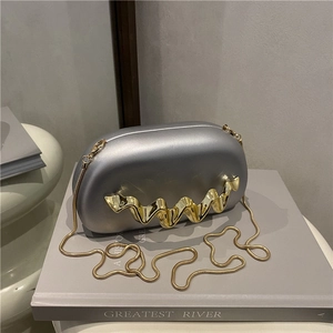 Silver acrylic wave evening bag with gold chain strap shown on a minimalist grey background