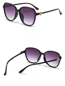 Detail of black oversized sunglasses featuring a gold floral hinge and gradient lens