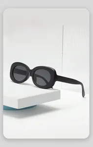 Close-up of matte black oversized sunglasses on a minimalist white display stand