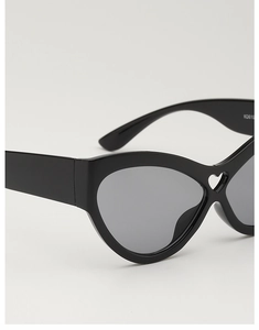 Détail de lunettes de soleil œil-de-chat noires avec une forme de cœur creux sur le pont