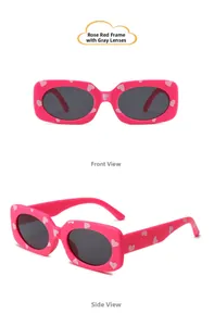 Close-up of kids heart pattern sunglasses with rose red frames and grey lenses