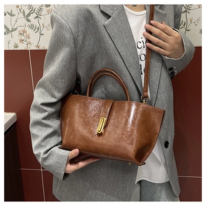 Detail view of a vintage dark brown tote bag with gold metal buckle and glossy leather texture