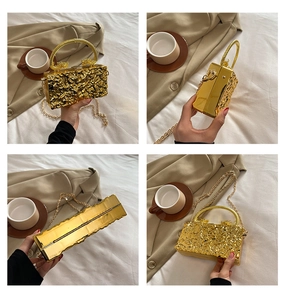 Close-up of golden liquid texture acrylic box bag with dragon handle and metal chain strap