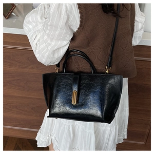 Détail d'un cabas noir rétro avec texture cuir brillant et fermoir en métal doré