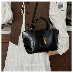 Détail du sac vintage en cuir ciré noir avec boucle ovale dorée et doubles anses élégantes