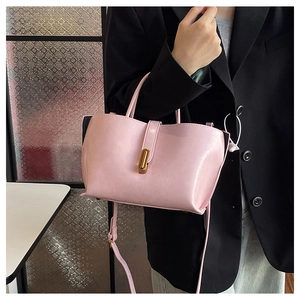 Macro view of light pink tote bag featuring a gold metal lock and leather texture details