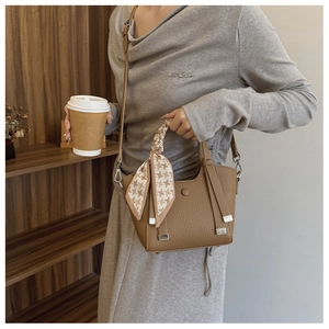 Detail of light brown lychee leather bucket bag with houndstooth silk scarf on handle