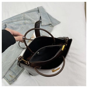 Détail du sac cabas marron foncé montrant la pochette zippée et les garnitures dorées