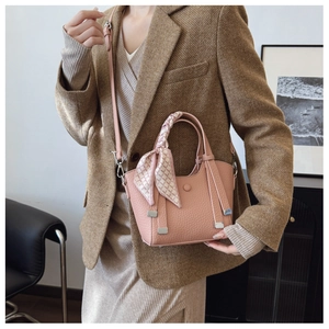 Detail of pink textured leather bucket bag with silk scarf handle and silver hardware