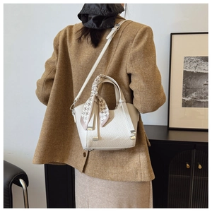 Detail of white lychee leather bucket bag with decorative silk scarf on the handle