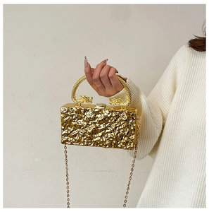 Detail of gold evening clutch with dragon handles and wrinkled metal texture