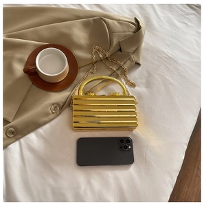 Golden hard-shell evening bag with wave texture and dragon handle shown with accessories