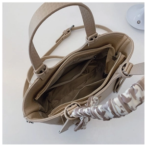 Interior view of beige bucket bag with compartments, inner zipper, and silk scarf detail