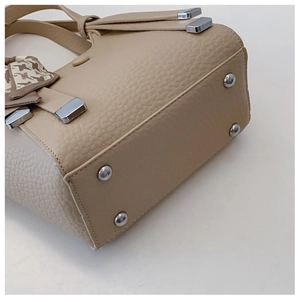 Detail of lychee pattern leather bag with protective metal studs and geometric scarf