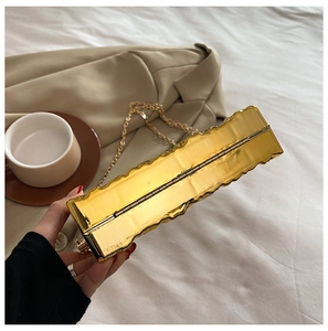 Macro detail of golden metal clutch featuring unique irregular wave textures and chain