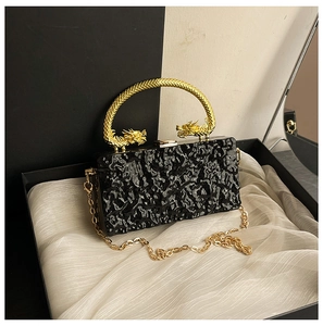 Detail view of black acrylic clutch with ice crack pattern and golden dragon handle