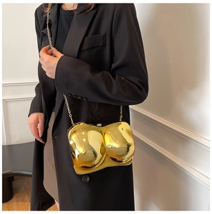 Detail of mirror gold bra-shaped clutch bag with sleek metallic chain strap