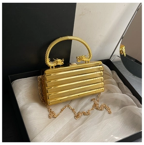 Detail of golden box clutch featuring dragon head handle and horizontal stripe texture