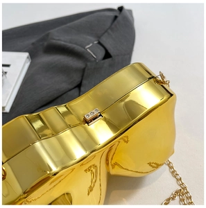 Macro shot of gold metallic clutch bag with three-diamond clasp and elegant chain strap