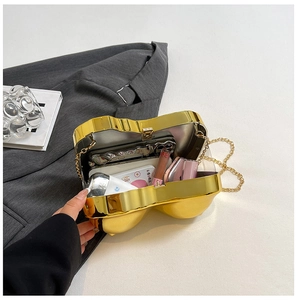 Internal view of gold heart-shaped metal clutch bag holding lipstick and makeup items