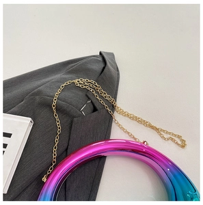 Macro shot of metallic gradient moon bag with golden chain on grey suit background