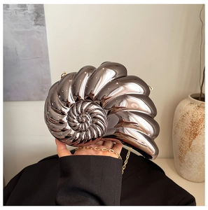 Detailed view of nautilus-shaped silver metallic clutch bag with golden chain strap