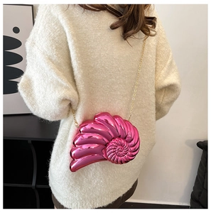 Detail of pink metallic nautilus shell crossbody bag with a delicate gold chain strap