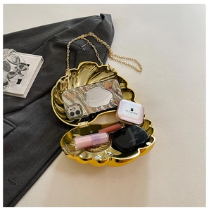 Macro view of golden shell chain bag showing storage space for phone and makeup